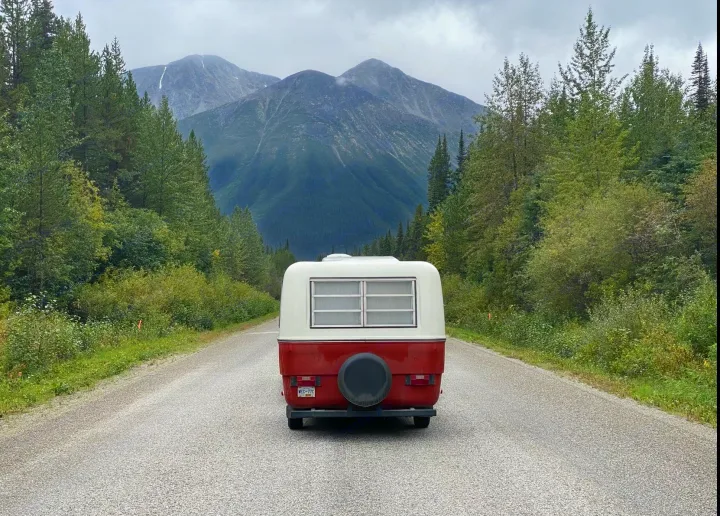 Scenic RV rental journey: a vintage camper on a mountain road through a dense forest. Perfect for a remote adventure.. Trillium Rv other 1975