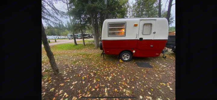 Vintage red/white RV rental at a fall campground, surrounded by trees and autumn leaves. Other RVs are visible.. Trillium Rv other 1975