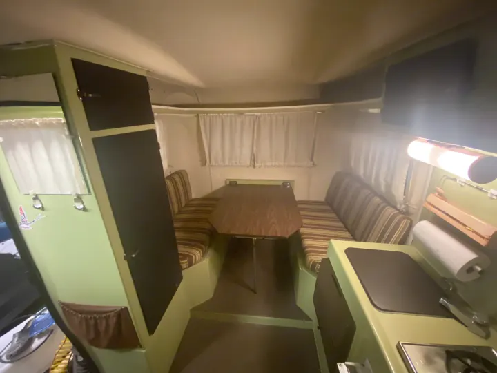 Cozy RV rental interior: dining booth, compact kitchen, and storage, featuring vintage green and brown accents.. Trillium Rv other 1975