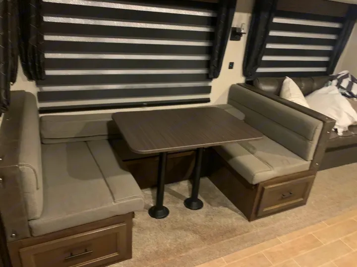 Cozy RV rental dinette featuring comfortable cushioned seating with under-bench storage and privacy blinds.. Forest River Cherokee Grey Wolf 2020
