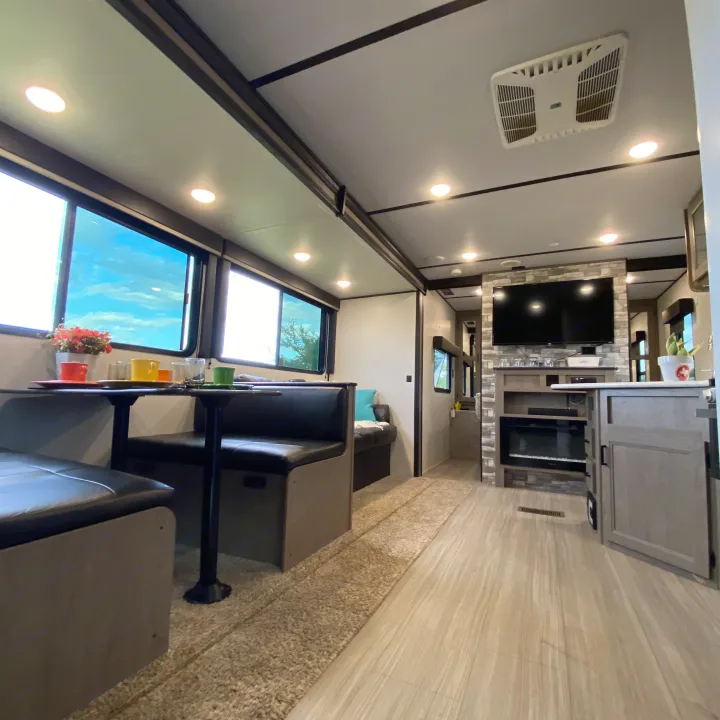 Explore this inviting RV rental interior, featuring a dining booth, modern kitchen, and living area with fireplace.. Keystone Hideout 2021