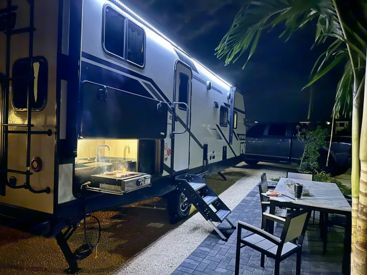 This rv rental boasts an outdoor kitchen with a grill sizzling burgers at night, complemented by bright exterior lights & a patio.. Winnebago Minnie 2301BH 2023