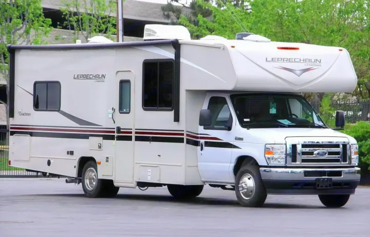 This white Coachmen Leprechaun Class C RV rental, with multiple windows and roof AC units, is parked and ready for travel.. Coachman Leprechaun 2022