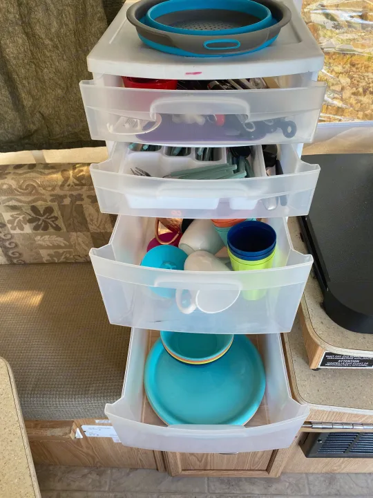 RV rental kitchen setup: clear drawers neatly organize compact camping dishes & utensils.. Palomino Yearling 2012
