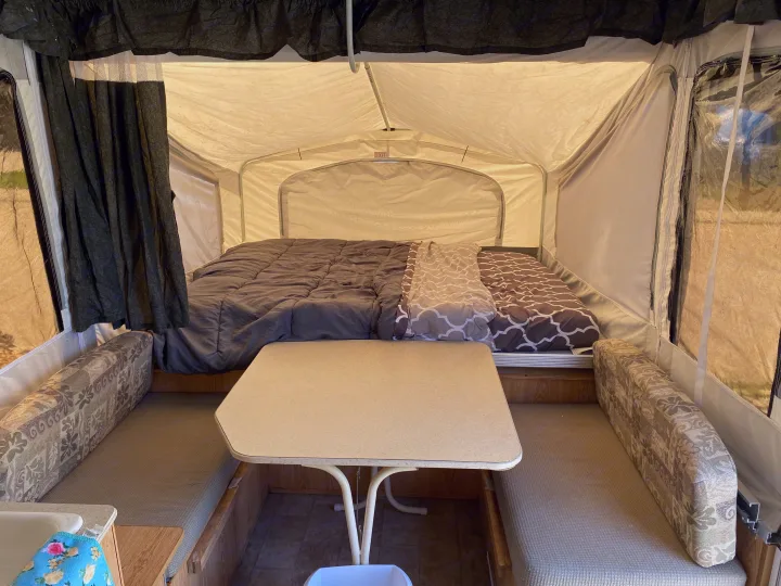 Spacious RV rental pop-up camper interior featuring comfortable beds, a central dinette, and tent-like walls.. Palomino Yearling 2012