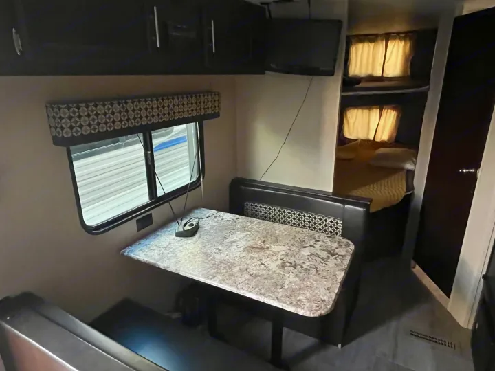 RV rental interior features: a spacious dinette, overhead cabinets, TV, and cozy bunk beds for comfortable travel.. Sportsmen LE 2018
