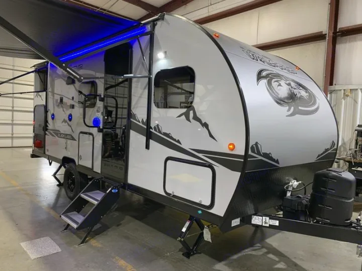 This sleek travel trailer, an ideal RV rental, features a black awning with blue LED lights and sturdy steps.. Forest River Cherokee Wolf Pup Black Label 2021