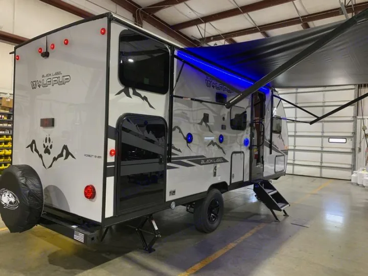 Modern grey travel trailer with extended awning and blue LED lights, ideal for your next RV rental adventure.. Forest River Cherokee Wolf Pup Black Label 2021