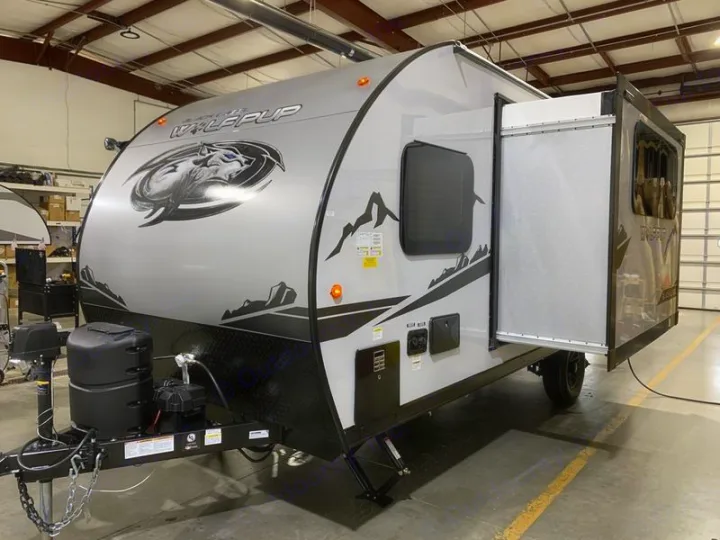 This grey Wolf Pup travel trailer is perfect for RV rental and camping adventures, featuring an open side bunk.. Forest River Cherokee Wolf Pup Black Label 2021