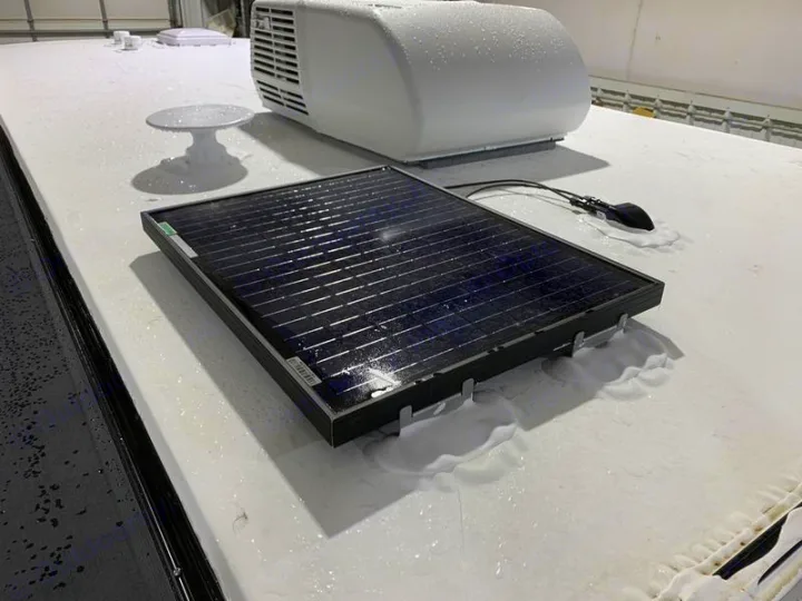 Top of an RV rental: features a mounted solar panel, AC unit, and satellite antenna on a wet roof.. Forest River Cherokee Wolf Pup Black Label 2021