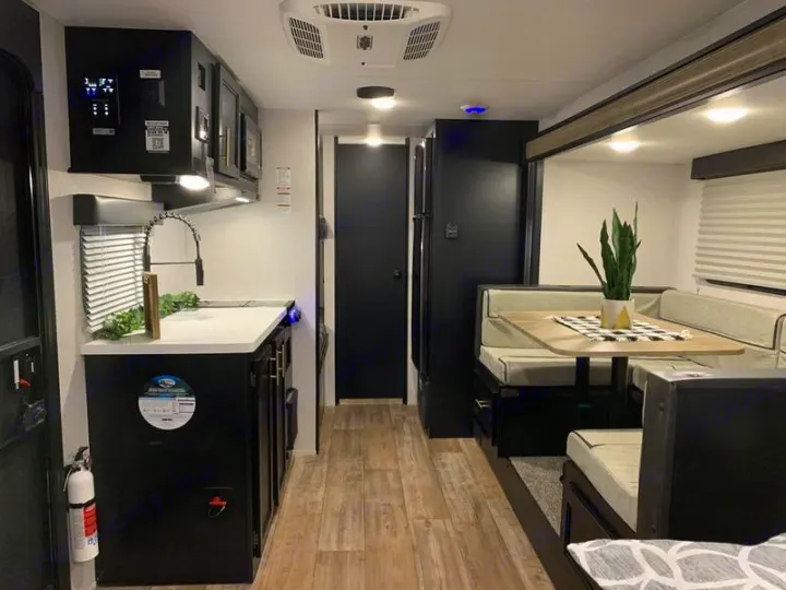 Interior of a modern rv rental showing a fully equipped kitchen and dinette with seating.. Forest River Cherokee Wolf Pup Black Label 2021