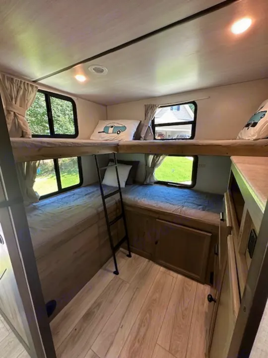 Spacious RV rental bunk room: multiple stacked beds, windows, and wood-look flooring for cozy stays.. Forest River Surveyor Legend 2022
