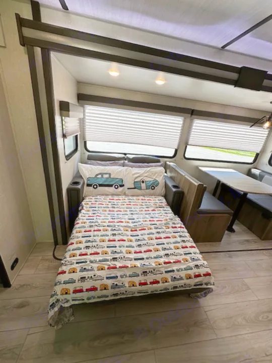 Bright RV rental interior featuring a fun car-themed bed, a cozy dinette, and large windows with blinds.. Forest River Surveyor Legend 2022