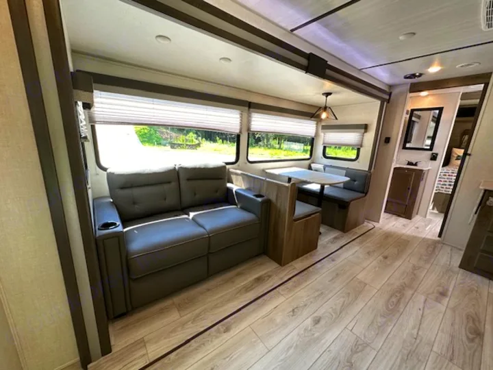 Bright, modern RV rental interior featuring a reclining sofa, dinette, and large windows.. Forest River Surveyor Legend 2022