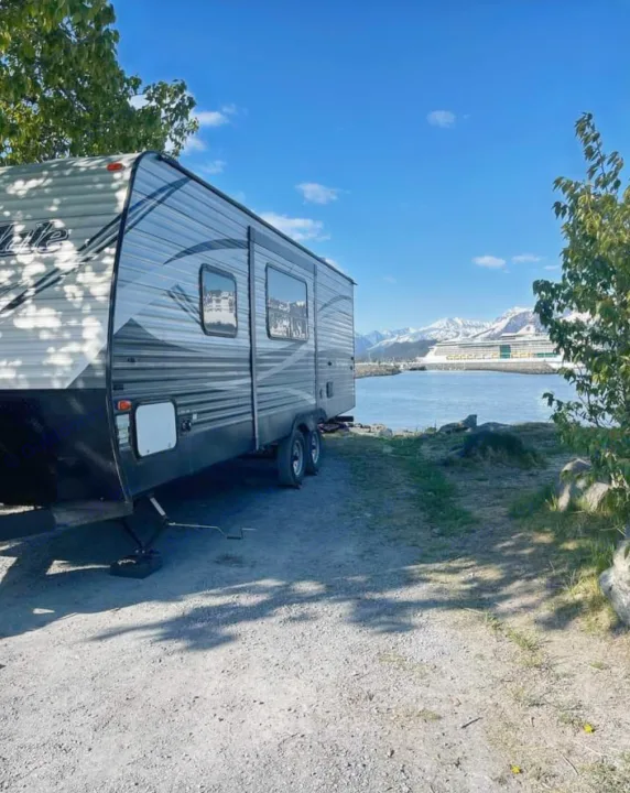 Scenic RV rental view: Travel trailer parked by a bay with a cruise ship & snowy mountains. Perfect waterfront camping.. Keystone RV Springdale 2018