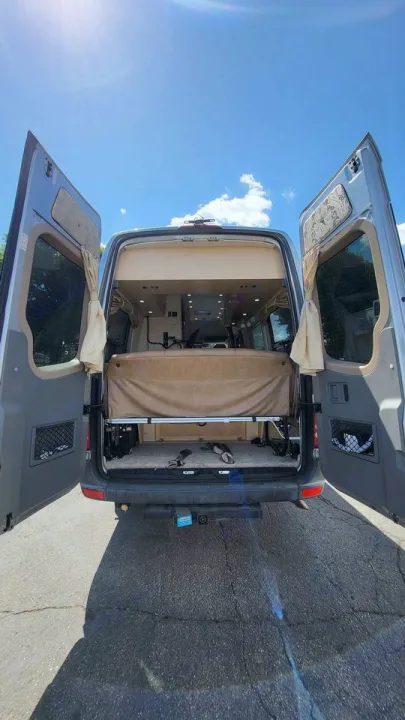 Explore this RV rental's spacious interior with open rear doors, revealing a cozy bed, ample storage, and adventure readiness.. Mercedes AS NEW SPRINTER 4 BERTH DISCOVERY AUTO TURBO DIESEL 2013