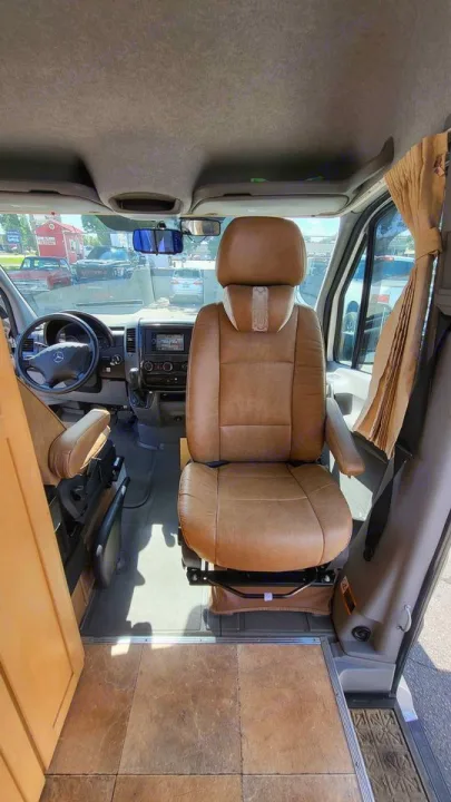 Step into this RV rental van's front cab. Features tan swivel captain's chairs, steering wheel, and dashboard for your journey.. Mercedes AS NEW SPRINTER 4 BERTH DISCOVERY AUTO TURBO DIESEL 2013