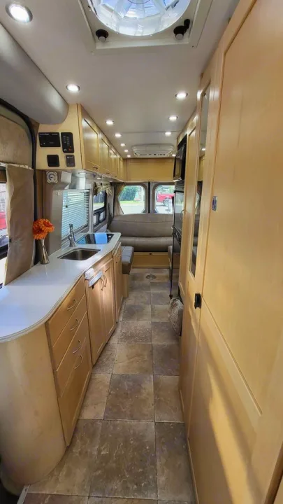 This modern rv rental interior has a functional kitchen with sink, light wood cabinetry, tiled floor, and a comfy lounge.. Mercedes AS NEW SPRINTER 4 BERTH DISCOVERY AUTO TURBO DIESEL 2013
