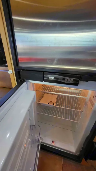 Empty RV rental refrigerator with open door, showing wire shelves and a top control panel for your next trip.. Mercedes AS NEW SPRINTER 4 BERTH DISCOVERY AUTO TURBO DIESEL 2013