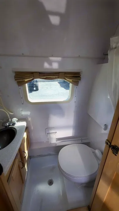 Compact RV rental bathroom featuring a toilet, sink vanity, and integrated shower area with a window and blind.. Mercedes AS NEW SPRINTER 4 BERTH DISCOVERY AUTO TURBO DIESEL 2013