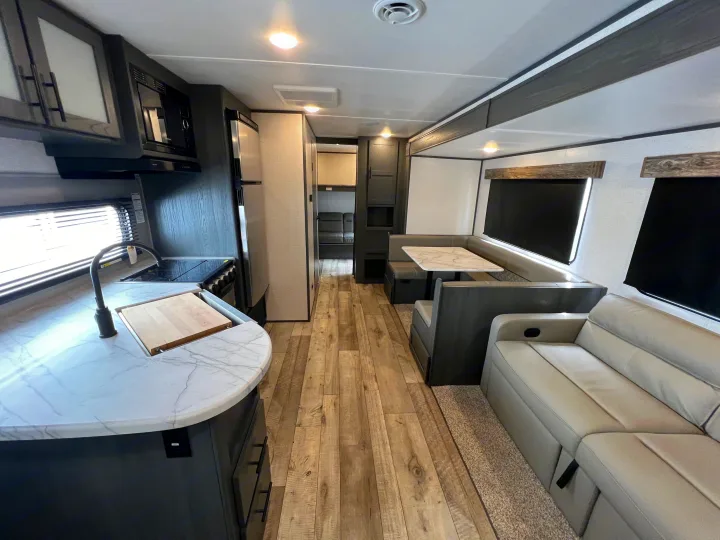 Modern RV rental interior with kitchen, dinette, and cozy sofa. A well-equipped travel trailer living space ready for your journey.. Dutchmen Aspen Trail 2022