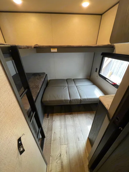 Modern RV rental interior featuring bunk beds, a convertible sofa bed, and wood-look flooring.. Dutchmen Aspen Trail 2022
