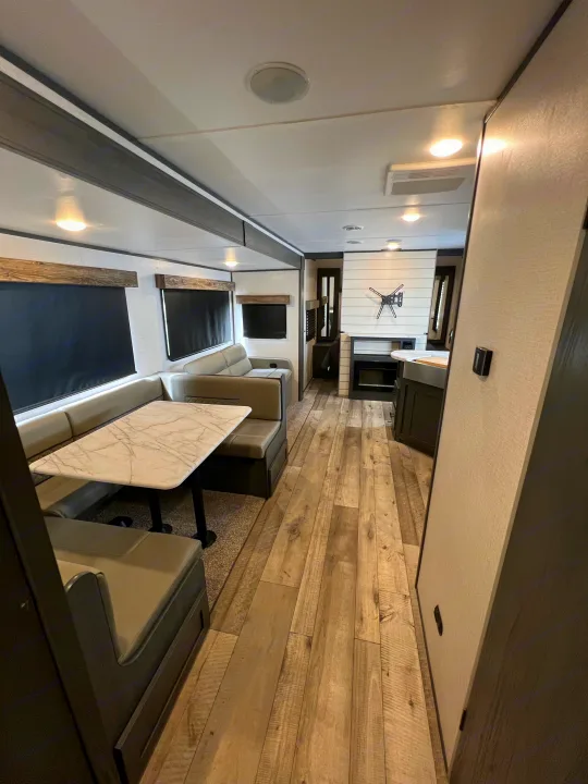 Explore this modern RV rental interior: cozy dinette, plush sofa, fireplace, and wood-style flooring for your next trip.. Dutchmen Aspen Trail 2022