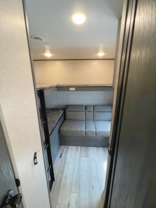 RV rental interior: cozy bunk beds, comfy sofa, and bright lighting in a compact space.. Dutchmen Aspen Trail 2022