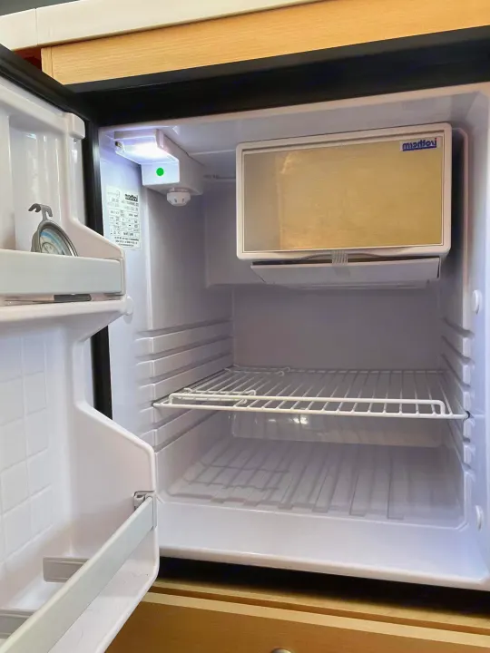 Open mini-fridge in an RV rental. View inside shows compact refrigerator space with freezer, light, and wire shelf.. nuCamp T@B 2020