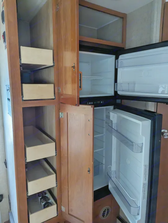 RV rental interior: Open fridge and pantry cabinet with multiple pull-out drawers for storage.. Winnebago Spirit 2019