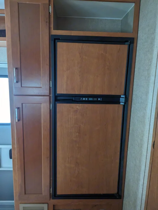 RV rental: wood-paneled refrigerator and adjacent cabinets, showcasing compact design and functional storage for travel.. Winnebago Spirit 2019