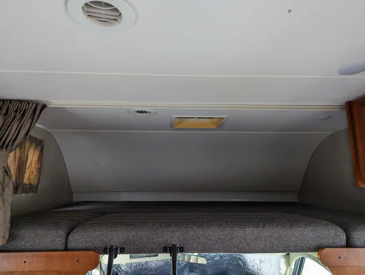 Cozy RV rental cab-over bunk bed with curtains and ceiling vent. Ideal for travel rest.. Winnebago Spirit 2019