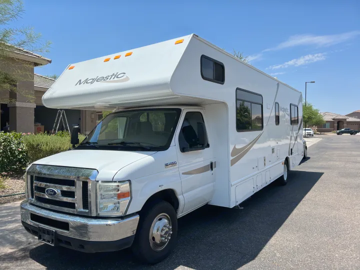 White Majestic Ford E-450 Class C RV rental parked on a sunny day in a residential area.. Thor Majestic 2013