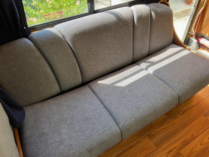 Spacious gray ribbed sofa inside an RV rental, ideal for comfortable travel and relaxation.. Thor Majestic 2013