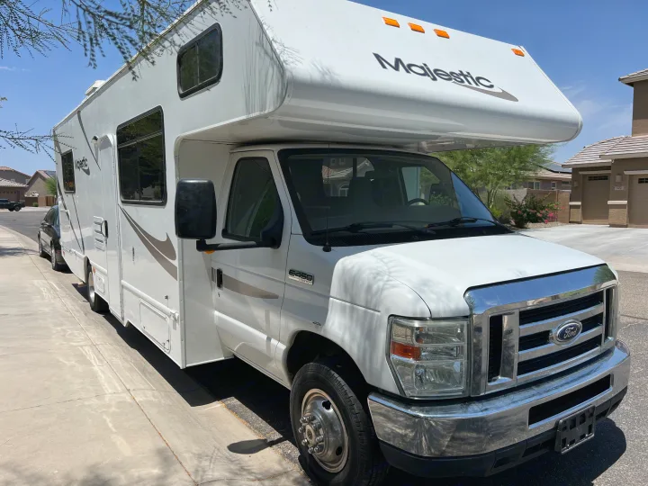 White Majestic Class C RV rental, a Ford E-450 Super Duty, parked on a sunny residential street.. Thor Majestic 2013