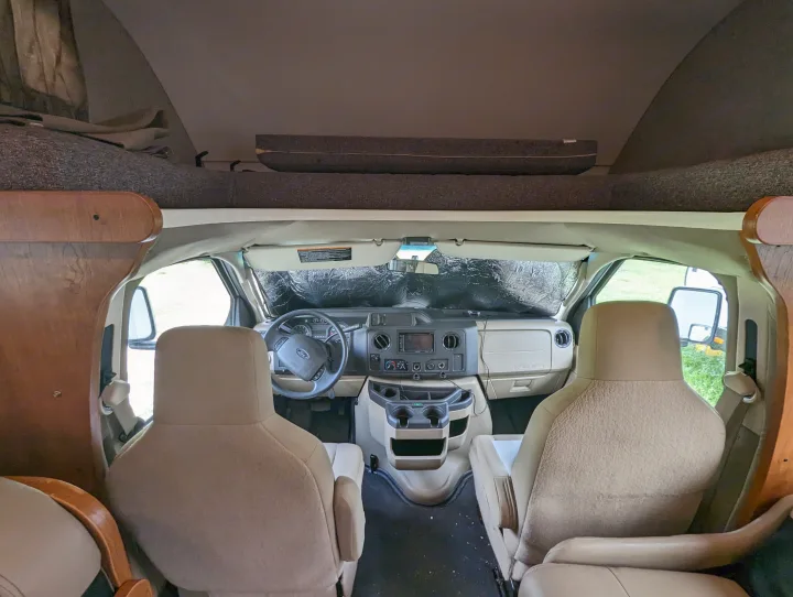 Step inside this RV rental's cozy front cabin! Features driver/passenger seats, dashboard, and an overhead bunk.. Winnebago Spirit 2019