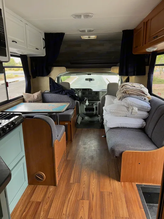Inside a well-appointed rv rental: kitchen, dinette with map table, and cozy seating looking towards the cockpit.. Thor Majestic 2013
