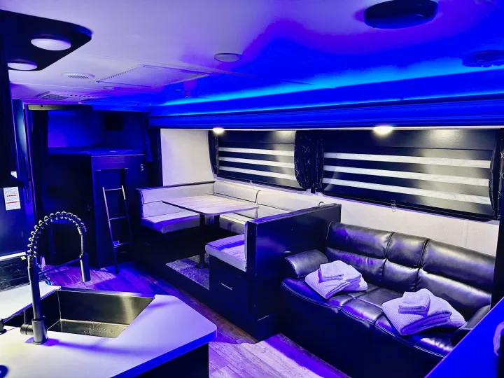 Experience a stylish **rv rental** interior: blue-lit dinette, comfy sofa with towels, kitchen sink, & bunk beds for cozy adventures.. Forest River Cherokee Grey Wolf Black Label 2021