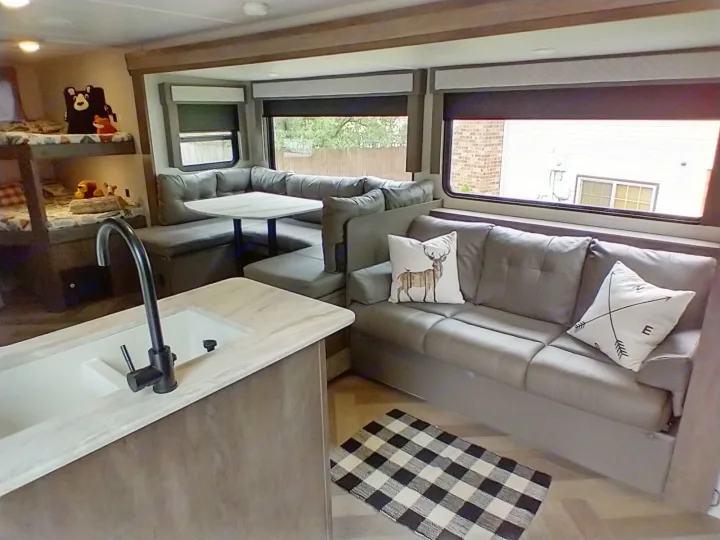 Spacious RV rental interior featuring bunk beds, a dinette, modern kitchen sink, and comfortable sofa with decor.. Forest River Wildwood X-Lite 2020
