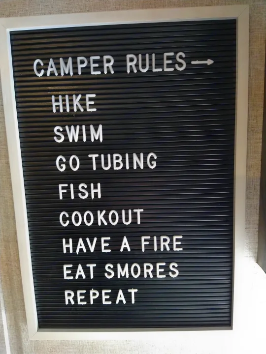 Inside an RV rental, a fun letter board lists 'Camper Rules' for outdoor adventures: Hike, Swim, Fish, S'mores, Repeat.. Forest River Wildwood X-Lite 2020