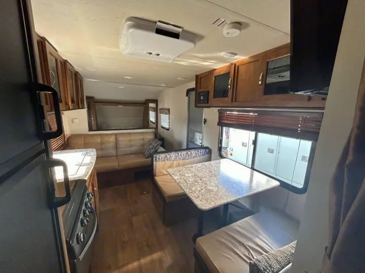 Inside a bright RV rental: living area with dinette, sofa, kitchen, and bunk beds visible. Comfortable, modern space.. Forest River Wildwood X-Lite 2017