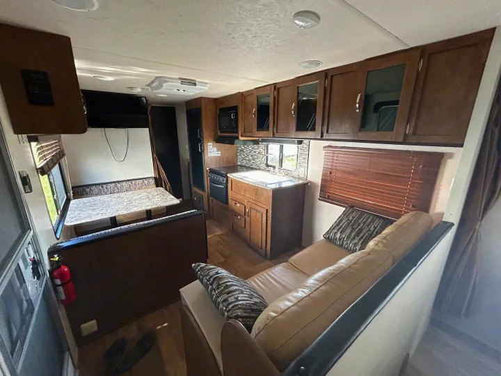 Spacious RV rental interior featuring a kitchen, dinette, and living area with a comfortable tan sofa.. Forest River Wildwood X-Lite 2017