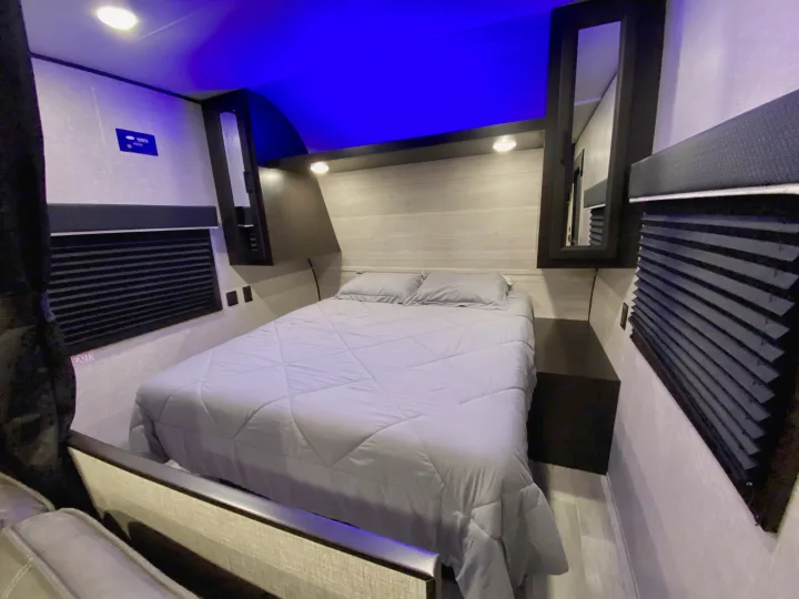 RV rental bedroom interior: featuring a cozy bed, window shades, built-in storage, and blue ambient lighting.. Jayco Jay Flight 2023
