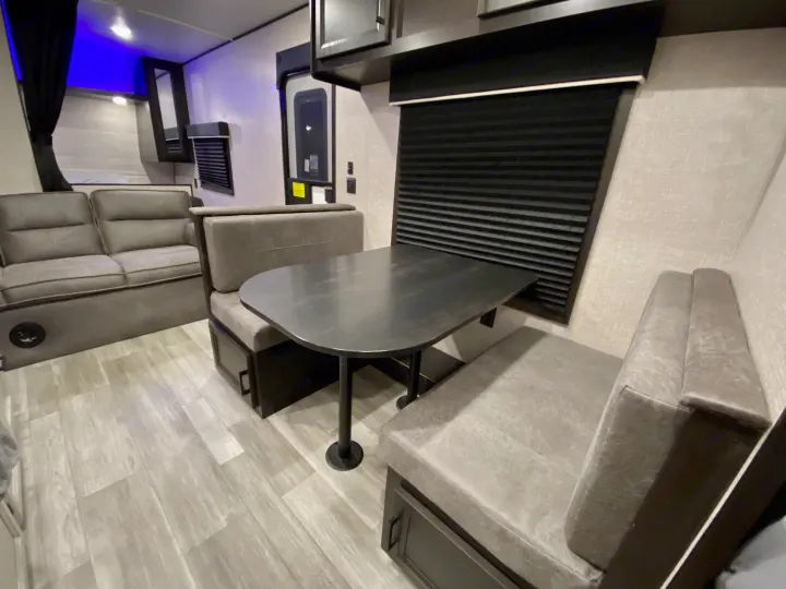 Spacious RV rental with a comfortable gray dinette, sofa, wood-look flooring, and blue LED lighting for a modern feel.. Jayco Jay Flight 2023
