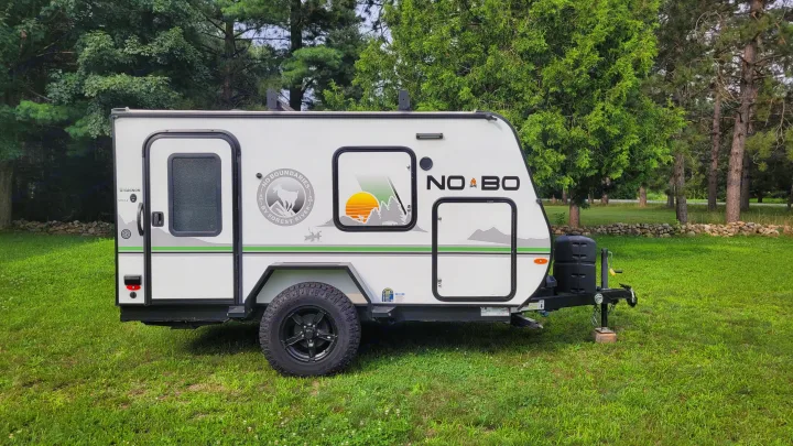 A modern Forest River NOBO compact travel trailer, an ideal RV rental for camping & adventures, parked on a lush green lawn.. Forest River NoBo 10.6 2022