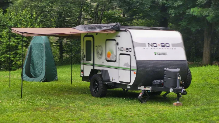 NO BO travel trailer RV rental with extended awning & privacy tent, set up on a grassy campsite near trees.. Forest River NoBo 10.6 2022