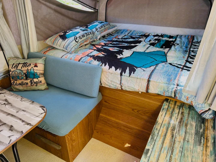 Cozy rv rental interior: bed with 'Camping' pillows, blue cushioned seating, & 'Adventure' pillow. Ready for your trip!. Cobra Flagstaff 1995