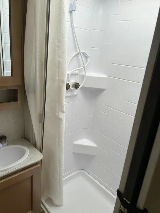 Clean RV rental bathroom featuring a compact shower with a white curtain and a small sink vanity.. R-Pod Hood River Edition 2020