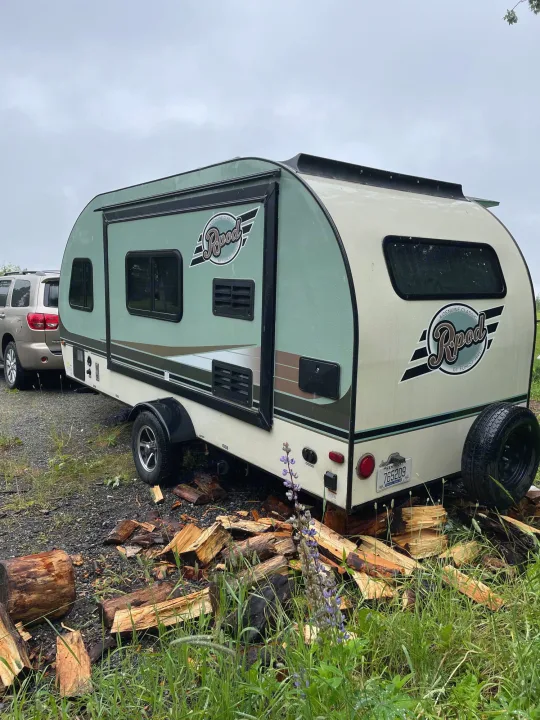 Green and cream R-pod travel trailer, ideal for an RV rental, parked with firewood on an overcast day.. R-Pod R-Pod Trailer 2017