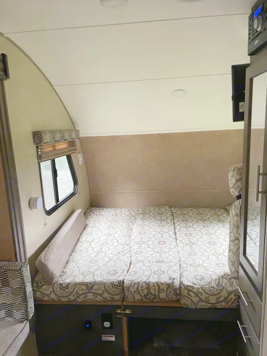 Compact RV rental interior featuring a patterned bed/sleeping area, perfect for travel. Window and storage visible.. R-Pod R-Pod Trailer 2017